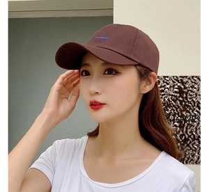 Detail view of a dark brown baseball cap worn by a model for a casual lifestyle look