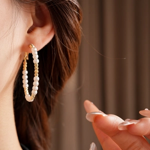 Macro detail of French vintage gold hoops with beaded pearls on a model ear