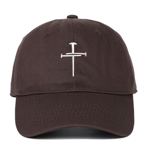 Detailed close-up of white cross embroidery on dark brown twill cotton baseball cap