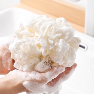 Soft white PE bath sponge foaming in hands for gentle skin cleaning and exfoliation
