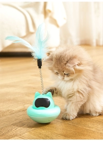 Detail of mint green tumbler cat toy with blue feather and spring on wooden floor