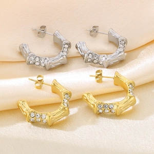 Detail of C-shaped bamboo texture earrings in gold and silver with inlaid cubic zirconia