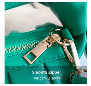 Detail shot of the bright green pleated bag with smooth golden zipper and metal hook hardware