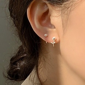 Détail macro de boucles d'oreilles tulipe en argent 925 sur l'oreille d'un modèle