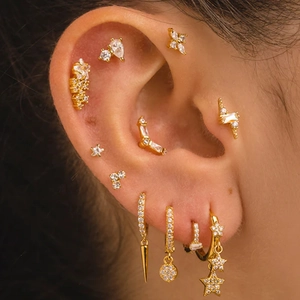 Macro shot of gold plated silver butterfly tassel ear piercings with zircon inlay detail
