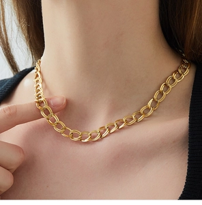 Primo piano della collana a catena dorata con maglie testurizzate sul collo di un modello