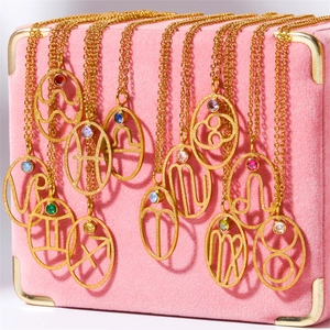 Gold zodiac pendant necklaces with colorful rhinestones on pink velvet jewelry box