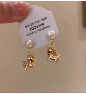 Detailed macro view of 925 silver golden pegasus earrings with white pearls and enamel