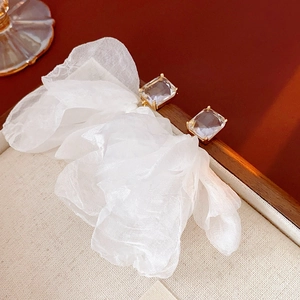 Detailaufnahme von Chiffon-Blumenohrringen mit quadratischem Zirkon auf Holztablett