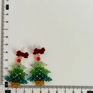 Detailed view of handmade beaded Christmas tree earrings with a red velvet bow and scale