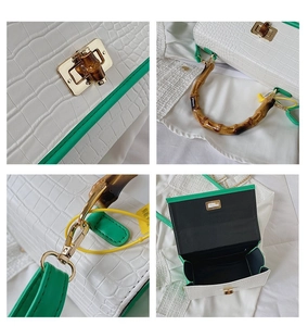 Detail of white crocodile pattern handbag with bamboo handle and green edge trim