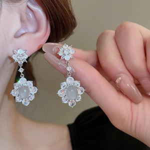 Détail macro de boucles d'oreilles fleurs argentées avec glands et pierres zircons