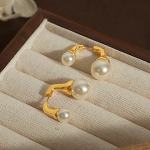 Orecchini a U dorati in rame con perle bianche in una scatola regalo di velluto beige