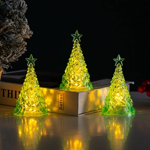 Detailed view of three mini glowing green crystal Christmas trees with warm LED light