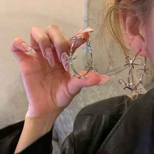 Detailed close-up of large silver hoop earrings featuring multiple bow knot accents