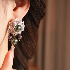 Detailed view of vintage resin floral earrings with pearl tassels and dark green beads