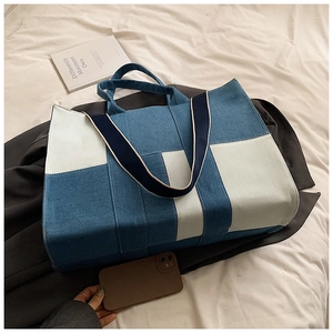Detail of blue and white patchwork denim tote bag with durable woven handles on fabric