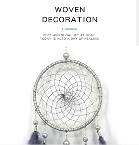 Macro detail of hand-woven dreamcatcher with grey feathers and silver beads wall decor