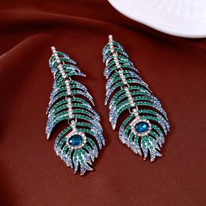 Macro detail of vintage silver feather earrings with emerald and blue gradient rhinestones