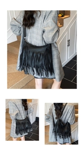 Detail of a black leather shoulder bag with vintage fringe and bohemian style accents