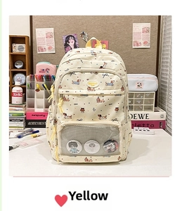 Detail view of the yellow school backpack with transparent mesh pocket and cute badges