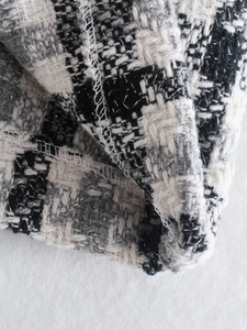 Dettaglio macro del tessuto tweed bianco e nero con fili metallici e cuciture rifinite