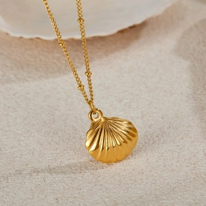 Elegant gold shell necklace on sand with beaded chain for minimalist beach style