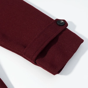 Detail of wine red wool coat cuff with texture and black button on white background
