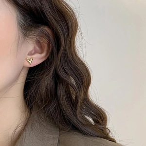 Elegant gold V-shaped chain tassel earrings worn by a model in a minimalist portrait