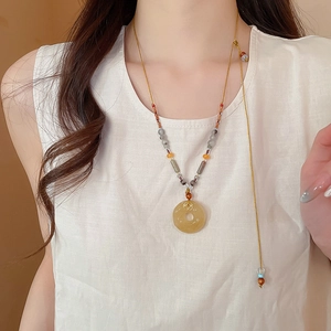 Détail d'un collier en agate grise avec pendentif ping'an kou jaune sur un mannequin