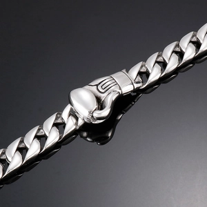 Macro detail of silver stainless steel Cuban chain bracelet with boxing glove clasp