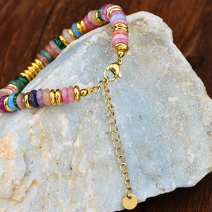 Close-up of colorful natural stone beaded bracelet with gold spacers on raw stone