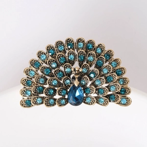 Detailed close-up of peacock brooch with blue rhinestones and teardrop gem on bronze base