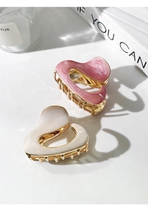 Detailed close-up of pink marble and pearly white heart-shaped metal hair claws on a table