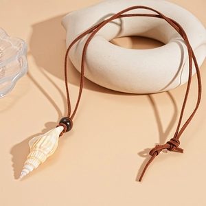 Detail of natural seashell and wooden bead pendant on a soft brown suede cord necklace