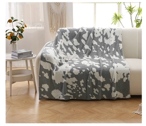 Detail of soft grey and white spotted plush blanket draped on a white home sofa