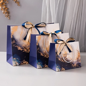 Three sizes of blue marble gift bags with gold ink patterns and silk ribbon handles