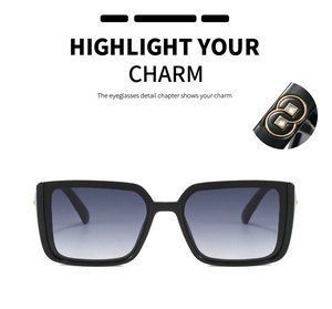 Close-up of black oversized sunglasses with gold geometric temple decoration and gradient lenses