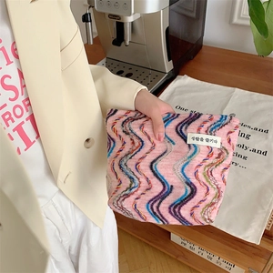 Close-up of pink knit makeup bag featuring colorful wavy embroidery and zipper closure