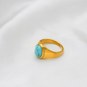 Detail of 18k gold plated signet ring with an oval turquoise stone on white velvet