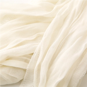Macro detail of breathable off-white scarf fabric with fine stitching and natural texture