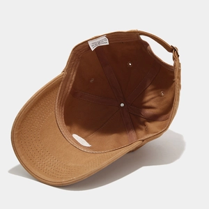 Internal detail of brown cotton baseball cap showing wash label and inner stitching