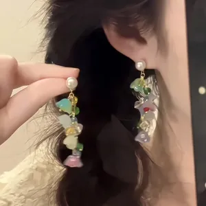 Detail view of gold-plated long dangle earrings with colorful translucent glass beads