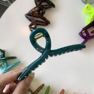 Detail of a large 11cm dark green hair claw clip showing the sturdy golden metal spring