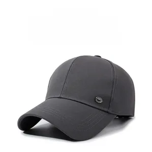 Close-up of a dark grey baseball cap featuring a round metal logo and reinforced stitching