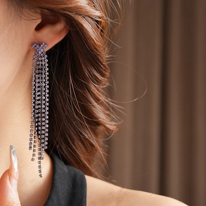 Gros plan de boucles d'oreilles pampilles à strass violets portées par un mannequin
