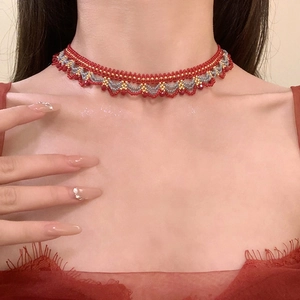Gros plan d'un ras de cou en perles fait main en rouge et or sur la clavicule