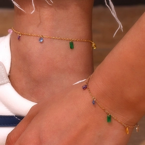 Close-up of gold chain anklet with colorful zircon charms worn on female ankle