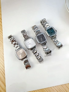 Flat lay of square quartz watches with colorful dials and silver steel straps