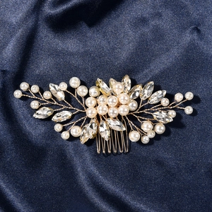Close-up of handmade bridal hair comb with gold wire, pearls, and rhinestones on blue silk